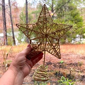 Gold metal star glittered star tree topper on spring.